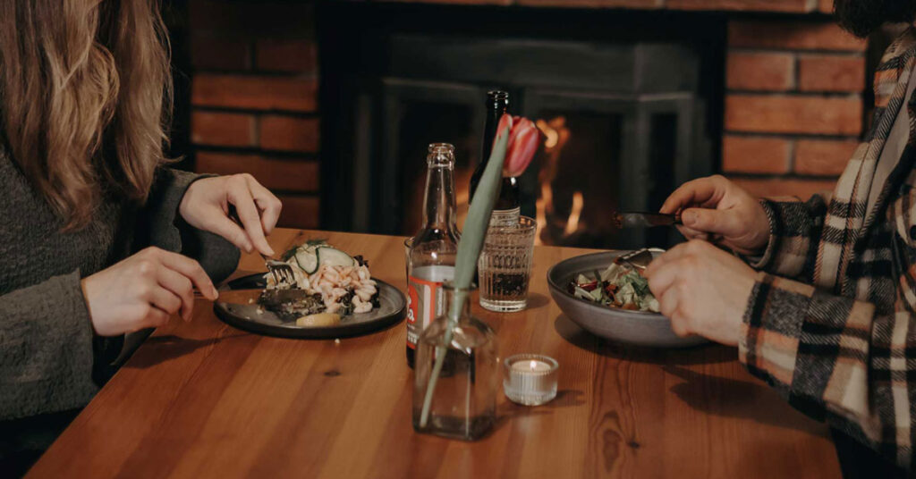 Två personer äter mat från Ryggåsstugan.